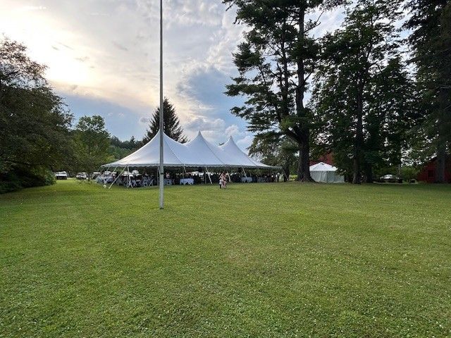 Tent on lawn with cook tent to right, parking lot behind tent